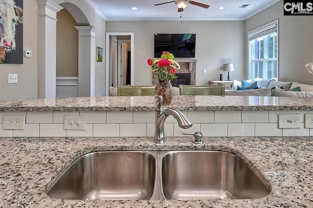 details with ornamental molding, a fireplace, sink, and ornate columns