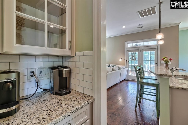 kitchen with sink, hanging light fixtures, dark hardwood / wood-style floors, light stone counters, and ornamental molding