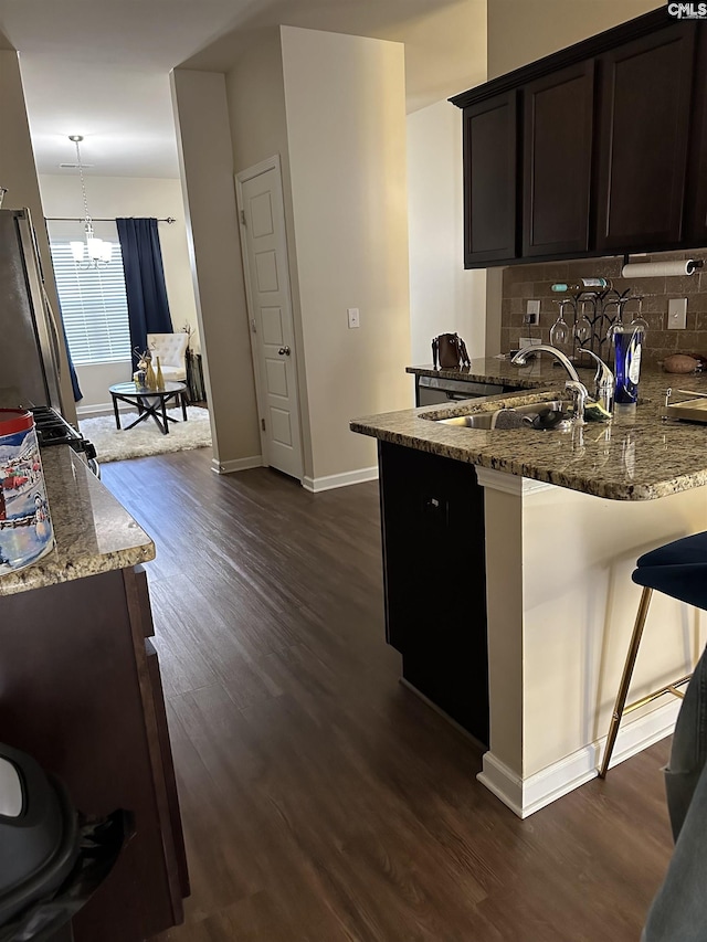 kitchen with pendant lighting, kitchen peninsula, decorative backsplash, light stone countertops, and a breakfast bar