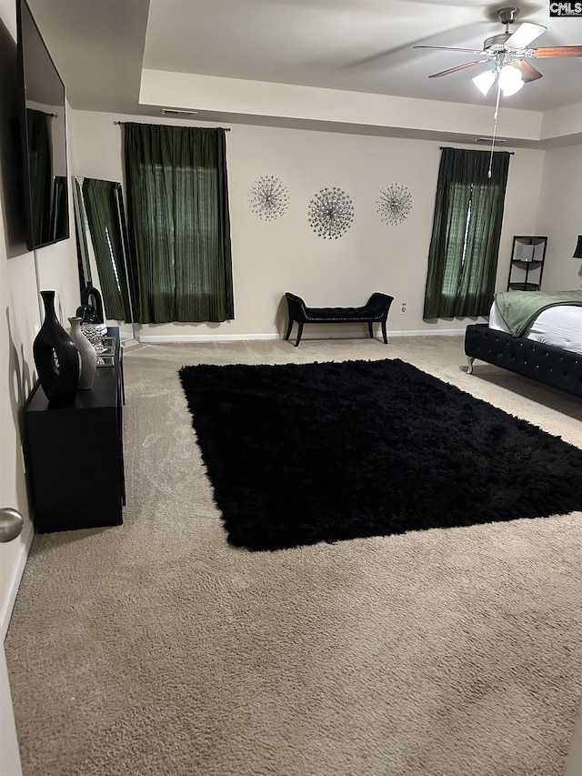 bedroom featuring carpet floors, ceiling fan, and a tray ceiling