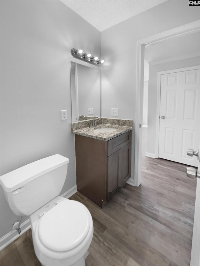 bathroom featuring wood-type flooring, a textured ceiling, toilet, and vanity