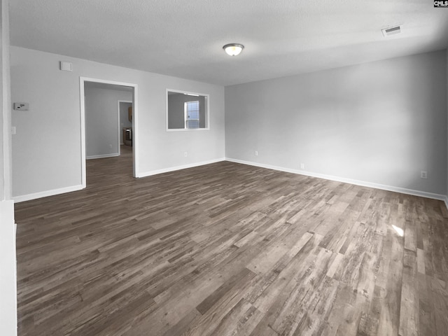 empty room with a textured ceiling and dark hardwood / wood-style floors