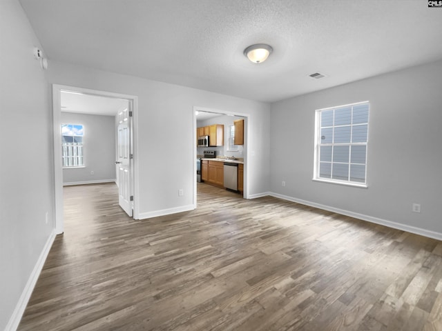 unfurnished living room with a textured ceiling and dark hardwood / wood-style flooring