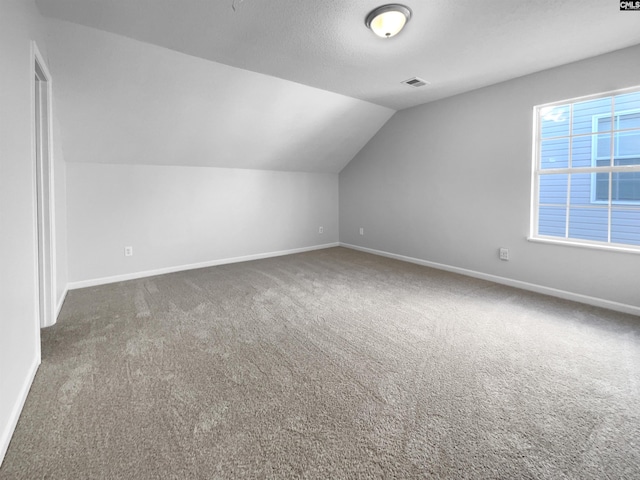 bonus room featuring vaulted ceiling and dark carpet