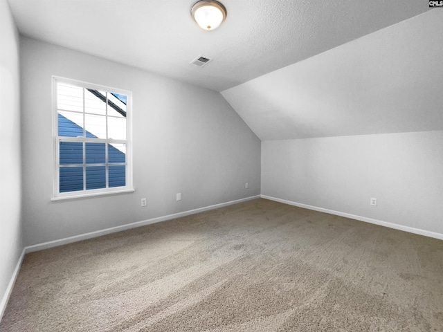 bonus room with carpet floors, vaulted ceiling, and a textured ceiling