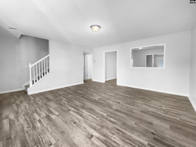 unfurnished living room with a textured ceiling and dark hardwood / wood-style floors