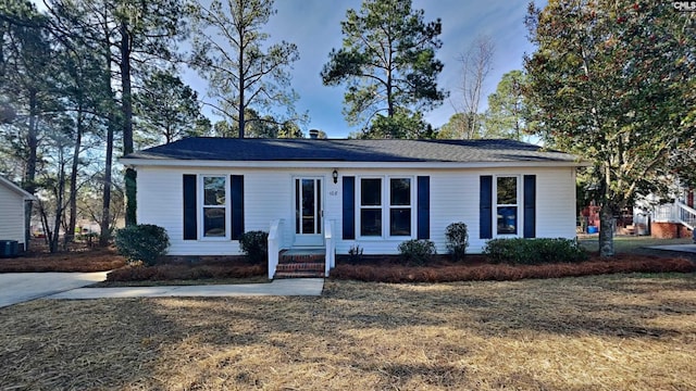 single story home with cooling unit and a front lawn