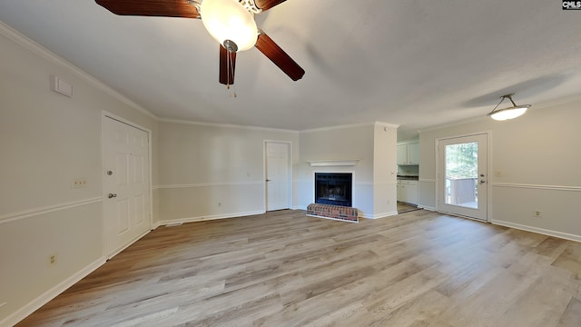 unfurnished living room with a fireplace, ceiling fan, ornamental molding, and light hardwood / wood-style flooring