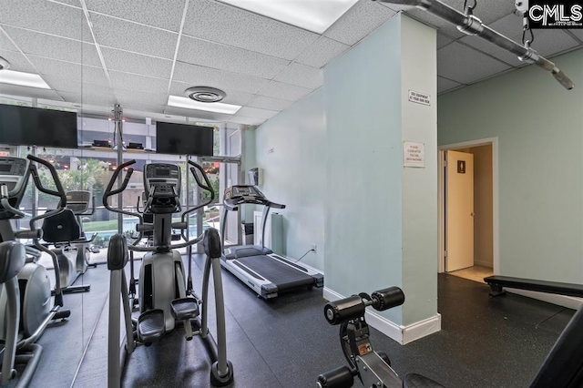 gym featuring a drop ceiling and a wall of windows