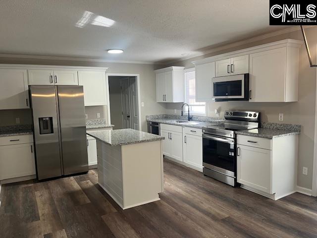 kitchen with stainless steel appliances, ornamental molding, a kitchen island, white cabinets, and sink