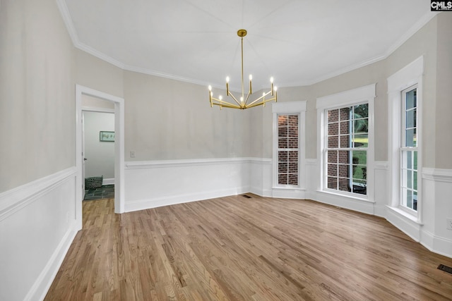 unfurnished dining area featuring wood-type flooring, an inviting chandelier, and crown molding