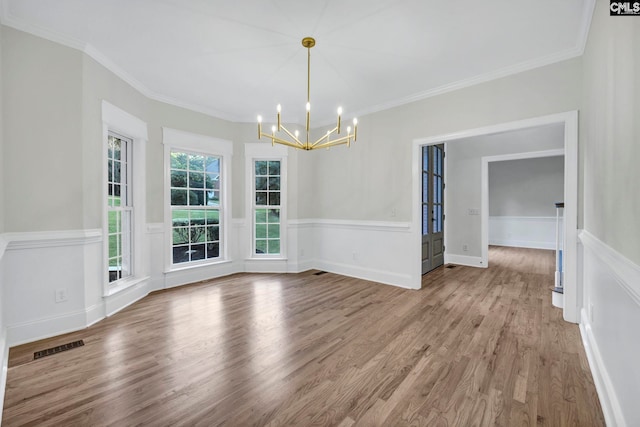 unfurnished dining area featuring wood-type flooring, an inviting chandelier, and crown molding