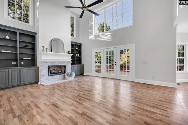 unfurnished living room with a high ceiling, ceiling fan, light hardwood / wood-style flooring, and a wealth of natural light