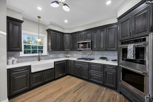 kitchen featuring wood-type flooring, stainless steel appliances, decorative backsplash, sink, and decorative light fixtures