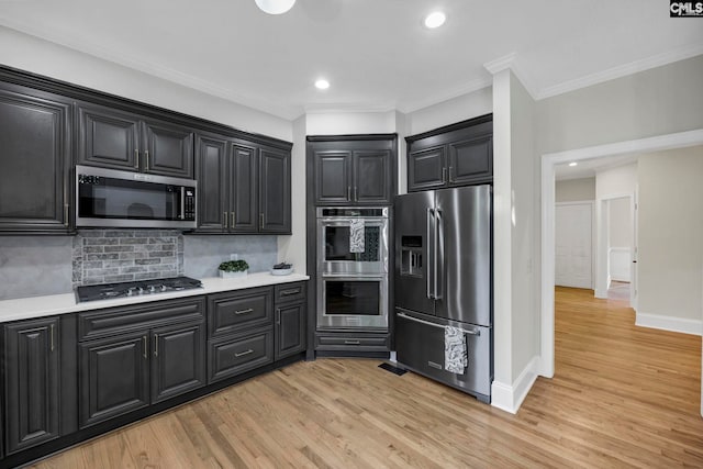 kitchen with appliances with stainless steel finishes, light hardwood / wood-style floors, ornamental molding, and backsplash