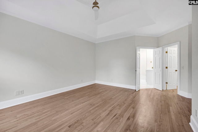 unfurnished room featuring ceiling fan, a tray ceiling, crown molding, and light hardwood / wood-style flooring