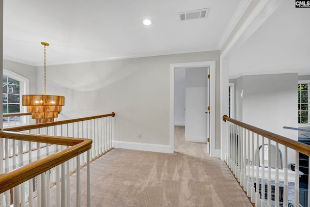 hall with ornamental molding, light colored carpet, and a notable chandelier