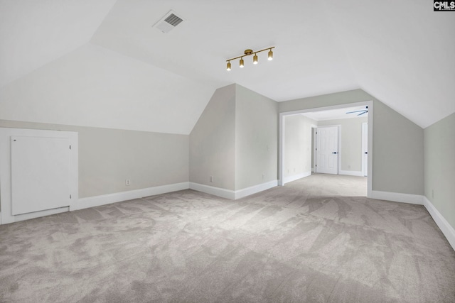 additional living space with light colored carpet, ceiling fan, and vaulted ceiling