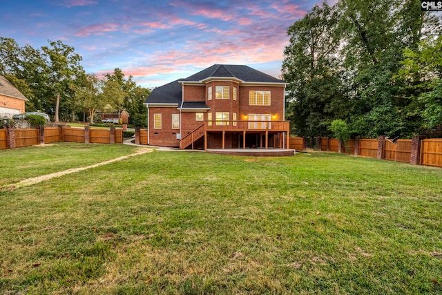 back house at dusk featuring a yard and a wooden deck