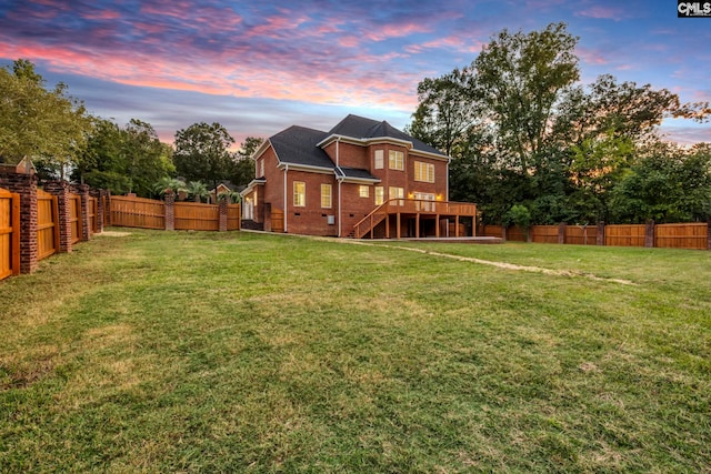 back house at dusk featuring a deck and a yard