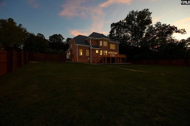 back house at dusk featuring a lawn