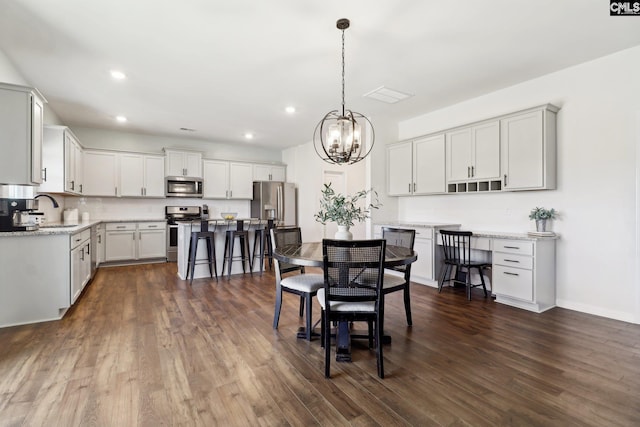 dining space featuring dark wood-type flooring, a notable chandelier, and sink