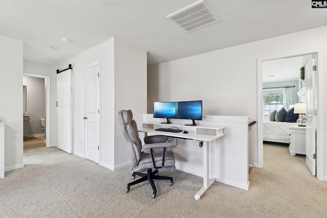 home office featuring light colored carpet and a barn door