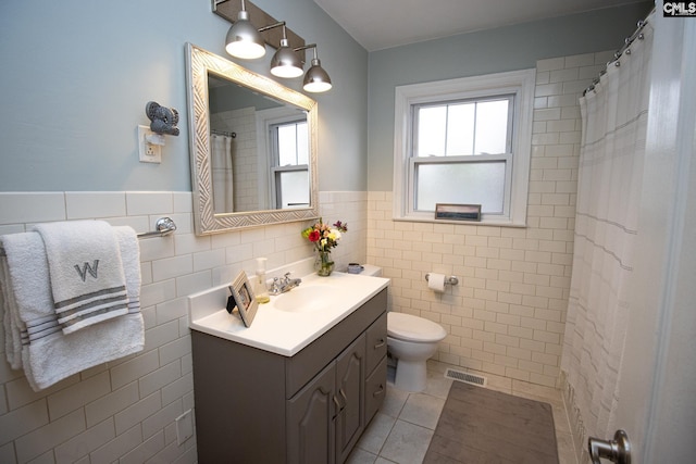 bathroom with tile walls, tile patterned flooring, toilet, and vanity