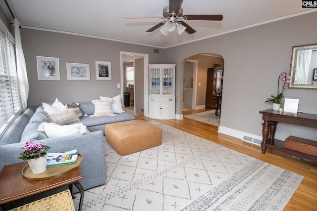 living room with ceiling fan, crown molding, and light hardwood / wood-style flooring