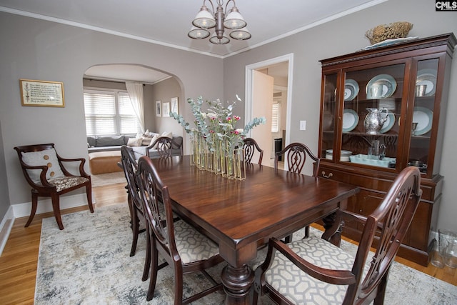 dining area featuring an inviting chandelier, ornamental molding, and light hardwood / wood-style flooring