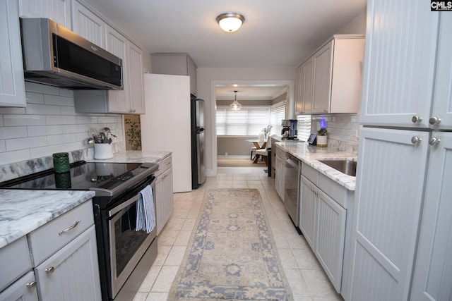 kitchen featuring stainless steel appliances, sink, tasteful backsplash, and light stone countertops