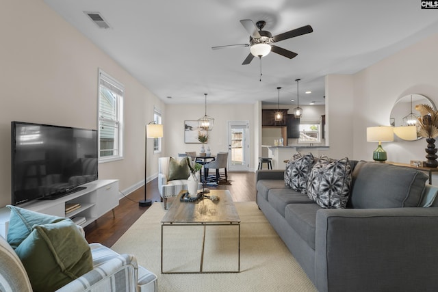 living room with ceiling fan with notable chandelier, hardwood / wood-style flooring, and a healthy amount of sunlight