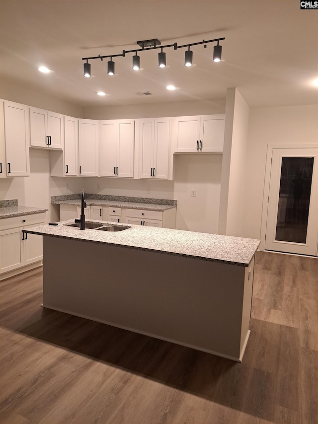 kitchen featuring white cabinetry, sink, an island with sink, and hardwood / wood-style flooring