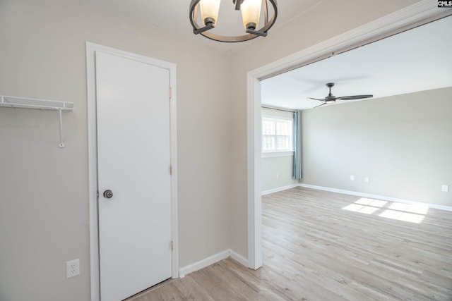 spare room featuring ceiling fan with notable chandelier and light hardwood / wood-style flooring