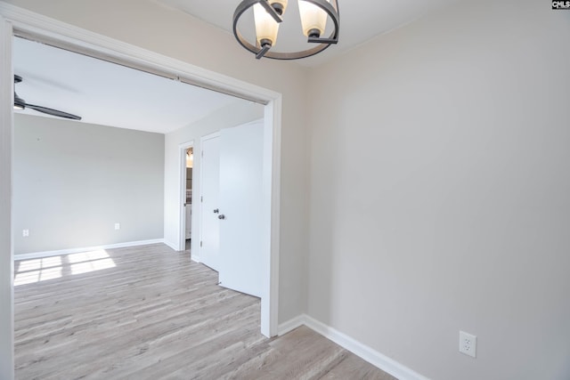 empty room with light hardwood / wood-style floors and ceiling fan with notable chandelier