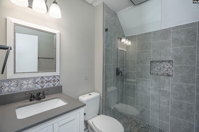 bathroom with tasteful backsplash, vanity, toilet, and a tile shower