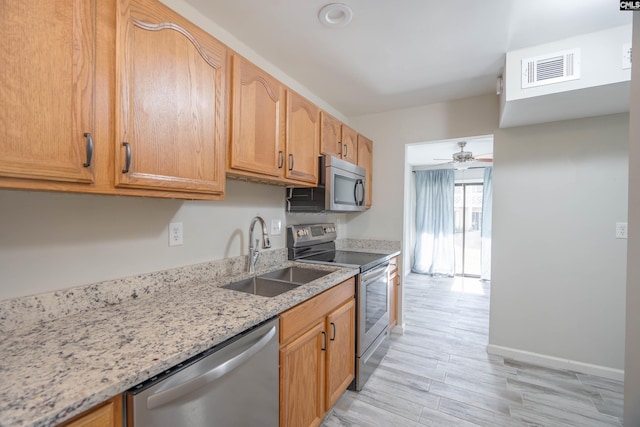 kitchen with ceiling fan, sink, light hardwood / wood-style flooring, stainless steel appliances, and light stone counters