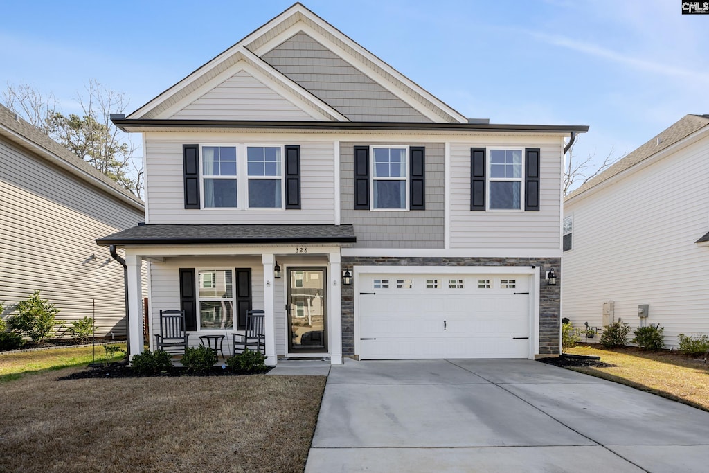 view of front of property featuring a garage, a front lawn, and a porch