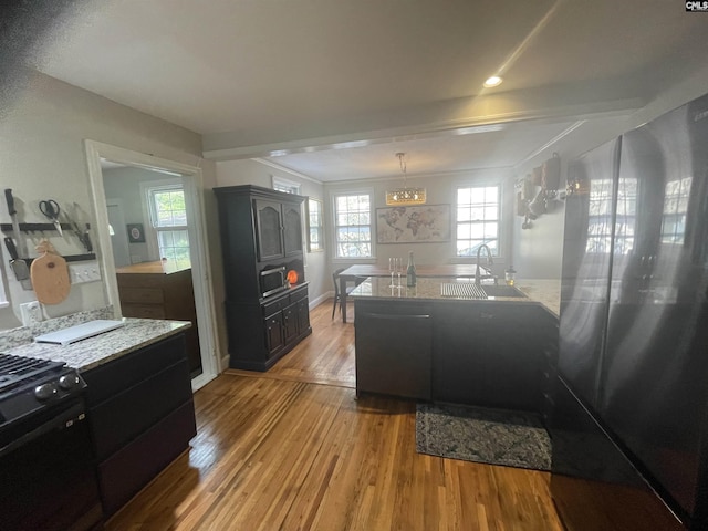 kitchen featuring an inviting chandelier, decorative light fixtures, black range with gas cooktop, light hardwood / wood-style flooring, and sink