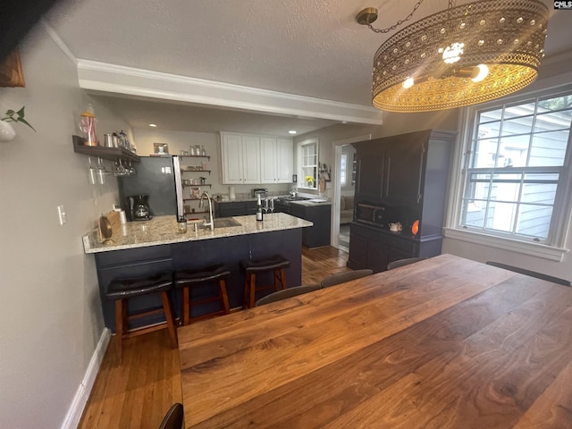 kitchen with dark wood-type flooring, stainless steel fridge, white cabinets, and sink