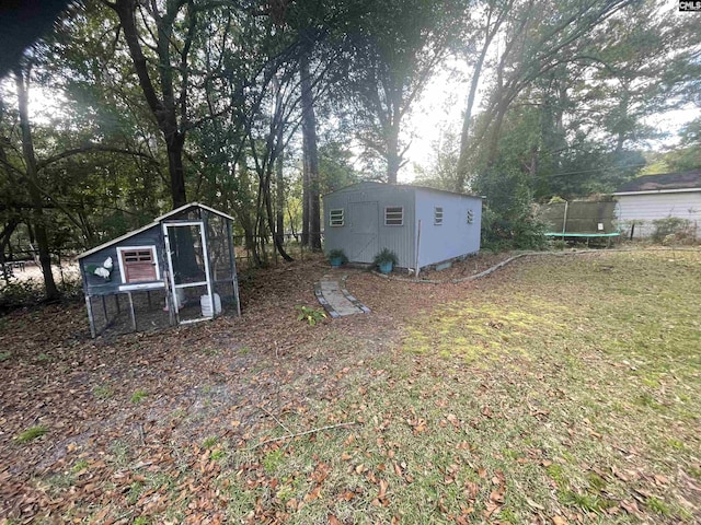 view of yard featuring a trampoline and a shed