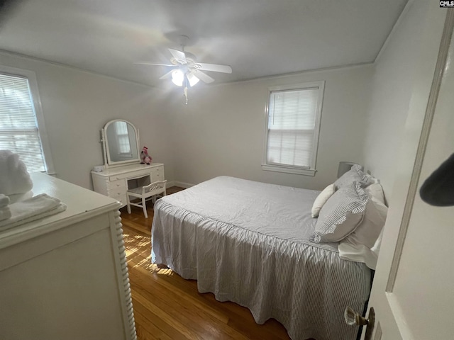 bedroom featuring ceiling fan, multiple windows, and hardwood / wood-style flooring