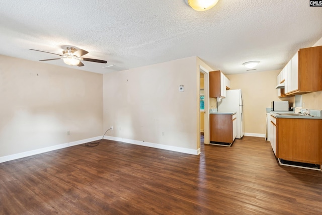 kitchen with a textured ceiling, dark wood-type flooring, white fridge, and ceiling fan