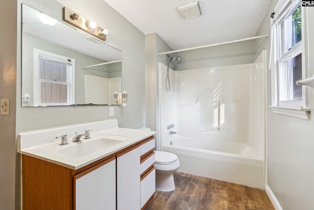 full bathroom with tub / shower combination, wood-type flooring, toilet, and a textured ceiling