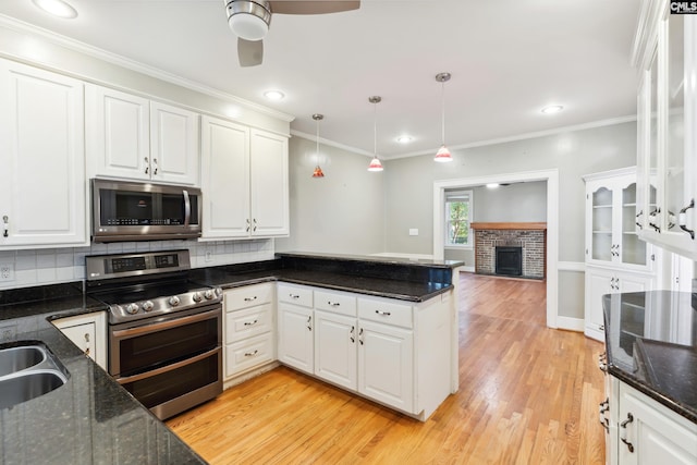 kitchen with decorative light fixtures, white cabinets, dark stone countertops, and stainless steel appliances