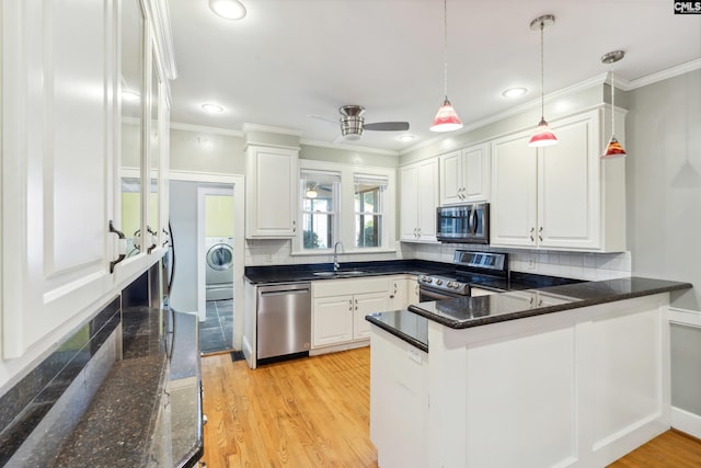 kitchen with pendant lighting, appliances with stainless steel finishes, white cabinetry, tasteful backsplash, and kitchen peninsula