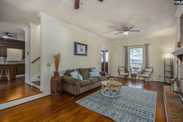 living room featuring a textured ceiling, dark hardwood / wood-style flooring, crown molding, and a fireplace