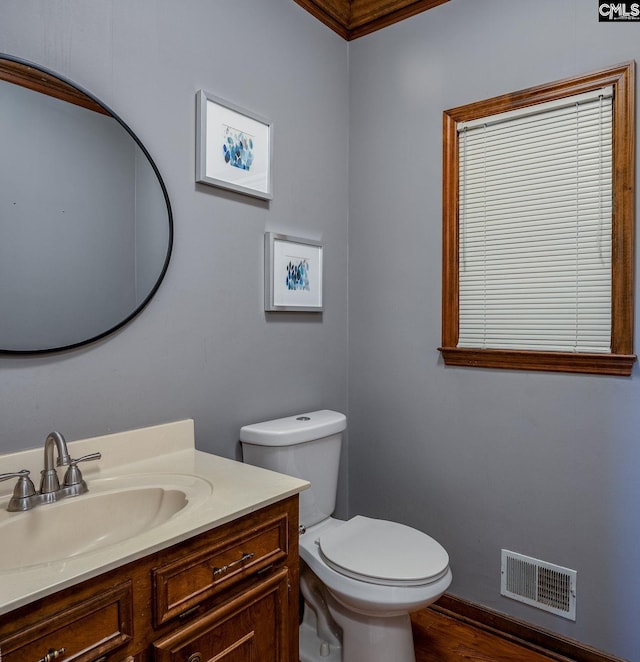 bathroom with wood-type flooring, toilet, vanity, and crown molding