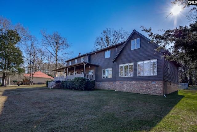 rear view of property featuring a yard and a porch