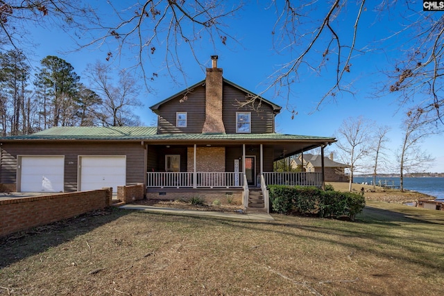 view of front facade with a water view, a front lawn, covered porch, and a garage